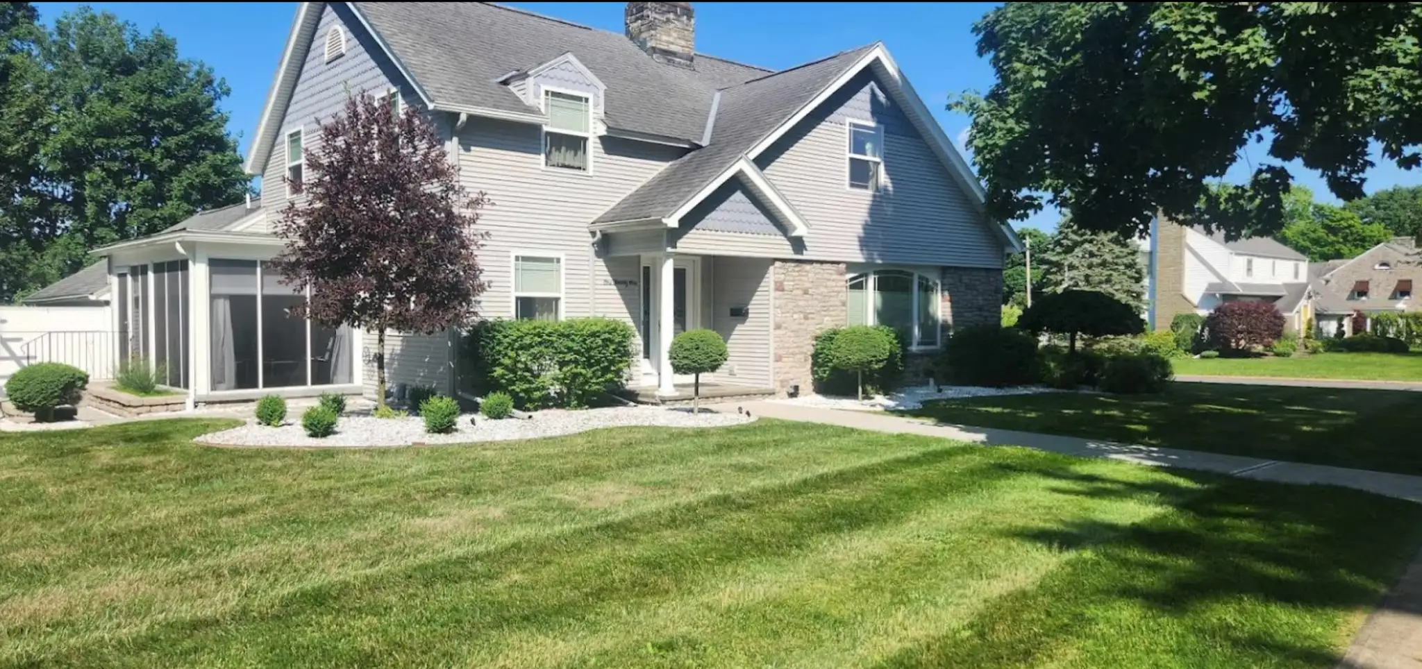 Neatly trimmed shrubs and hedges in front of a home after professional hedge trimming service in Utica, NY